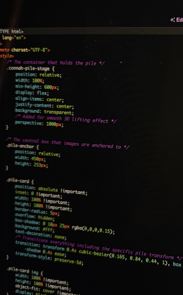 Close-up of a monitor showing custom frontend CSS styling and code blocks for a responsive 3D image pile web animation component.